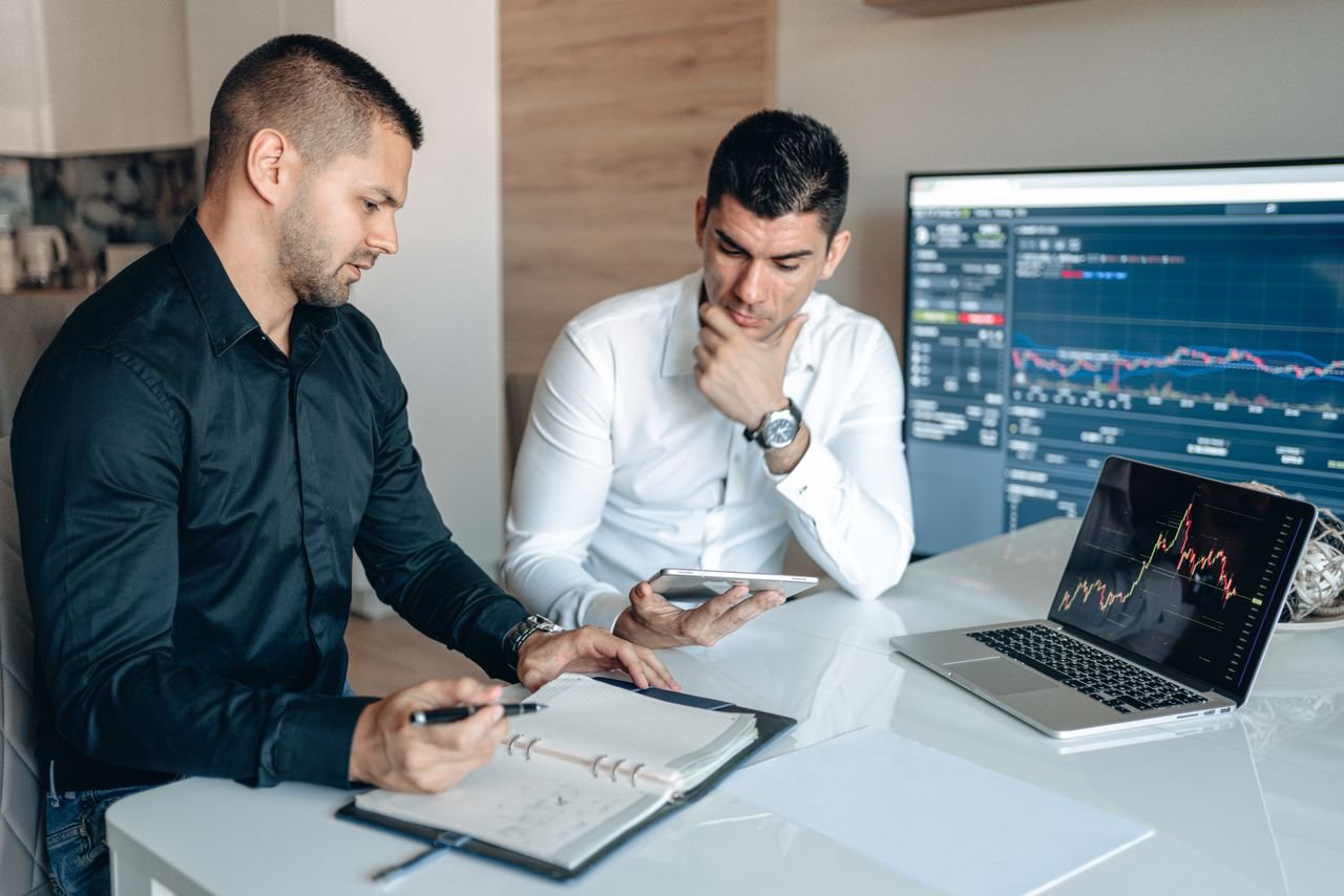 The Art of Drawing Readers In: Your attractive post title goes here Two businessmen discussing stock market analytics in a modern office setting.