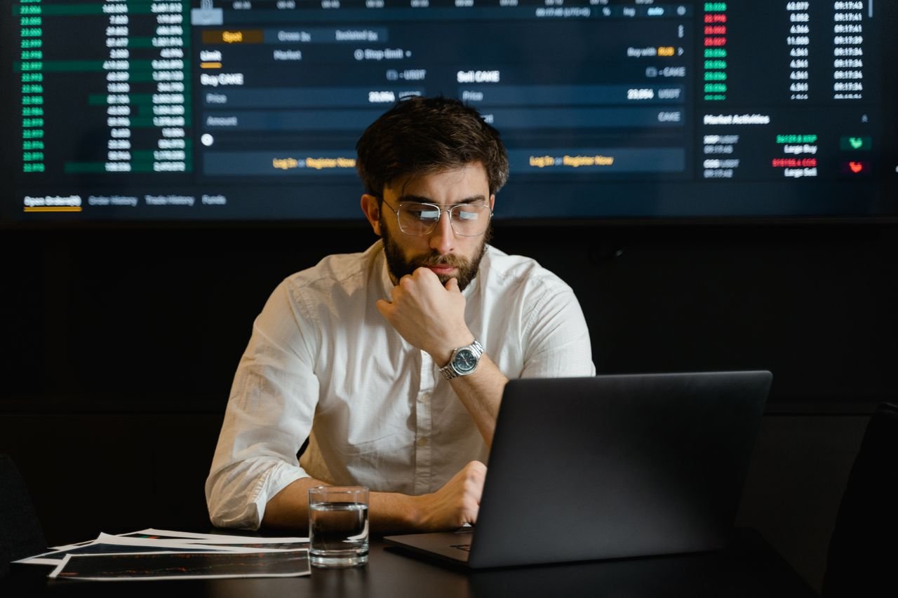 Mastering the First Impression: Your intriguing post title goes here A man intensely analyzing stock market data on a laptop in an office setting.